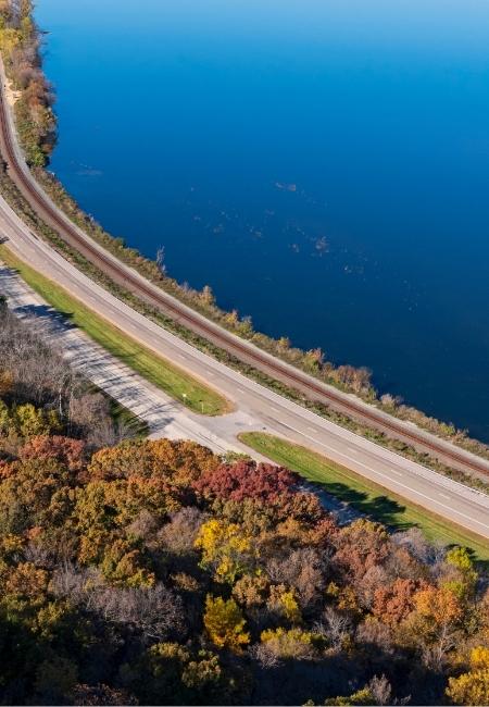 Am Highway 61 verläuft eine Straße entlang des Mississippi-Deltas, daneben liegt tiefblaues Wasser und herbstlicher Wald.