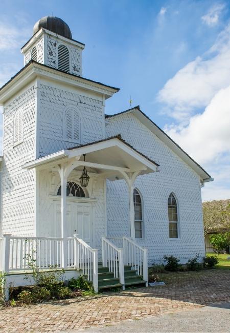 Die weiße Holzkapelle der Whitney Plantation in Wallace, Louisiana hat einen kleinen Turm, eine Veranda und schmale Fenster.