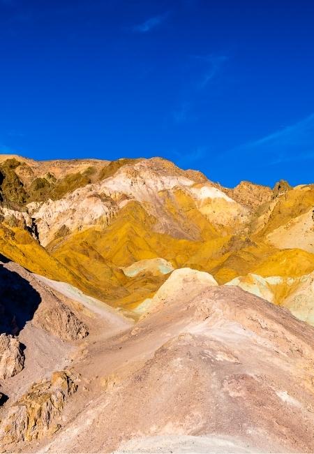 Im Death Valley Nationalpark leuchten gelbe und braune Felsformationen unter einem tiefblauen Himmel in klarer Wüstenluft.