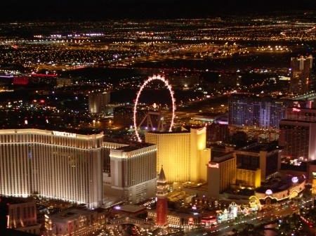 Über dem Las Vegas Strip leuchtet nachts das High Roller zwischen hellen Hotelanlagen und Stadtlichtern.