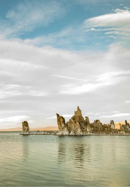 Am Mono Lake ragen helle Tufftürme aus dem ruhigen, grünlich schimmernden Wasser unter einem weiten Wolkenhimmel auf.