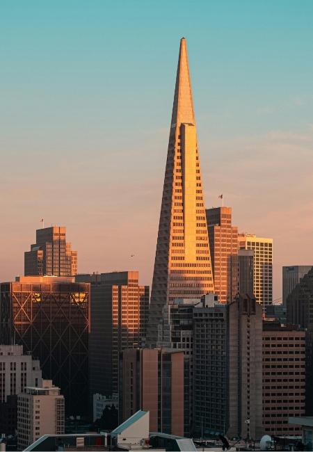 Die Transamerica Pyramid ragt im warmen Abendlicht über die Skyline von San Francisco unter klarem Himmel auf.