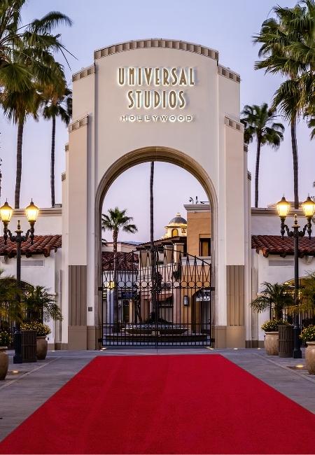 Vor dem Tor von Universal Studios Hollywood führt ein roter Teppich zwischen Palmen und Laternen zum Eingang.