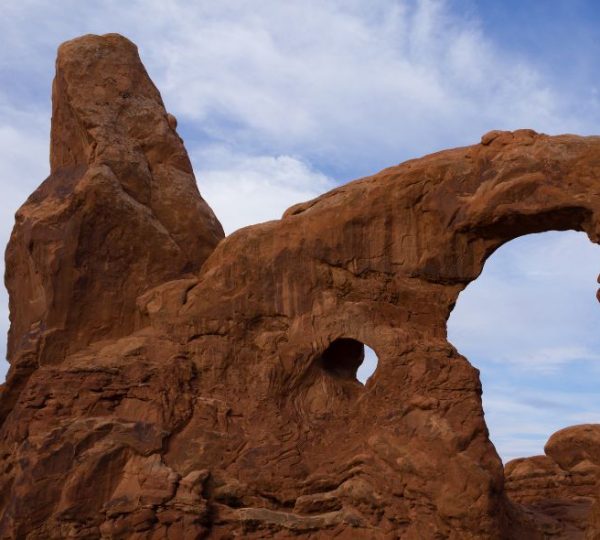 Eine markante rote Felsformation mit großem Bogen und kleiner Öffnung im Arches National Park während einer Canyon-Rundreise