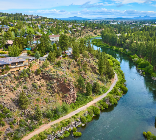 Luftaufnahme von Bend, Oregon, mit dem Deschutes River, bewaldeten Hängen, Wohnhäusern und einem Uferweg