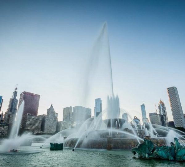 Hohe Wasserfontänen der Buckingham Fountain vor der Skyline von Chicago am Ufer des Grant Park im Sonnenlicht