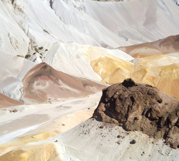 Helle vulkanische Hänge in den farbenprächtigen Painted Hills von Oregon mit einem dunklen Felsblock im Vordergrund