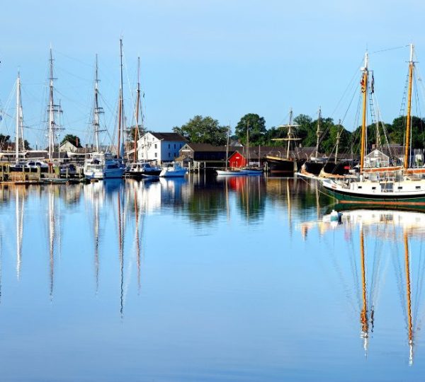 Ruhiger Hafen im Mystic Seaport in Connecticut mit historischen Segelschiffen und Spiegelungen im Wasser