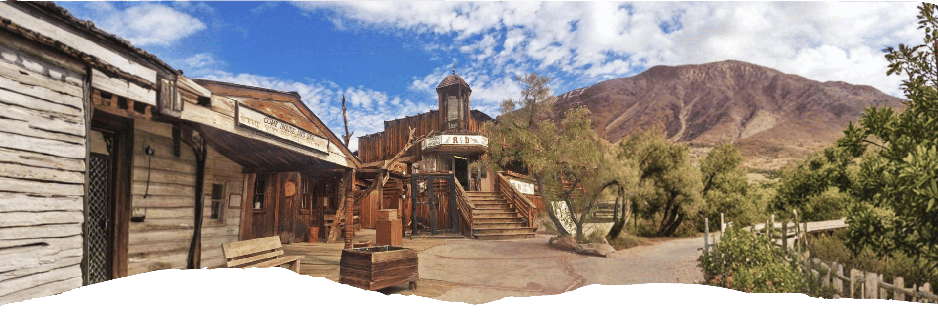 Historische Holzgebäude und eine alte Mine prägen Calico vor der kargen Berglandschaft der kalifornischen Mojave-Wüste.
