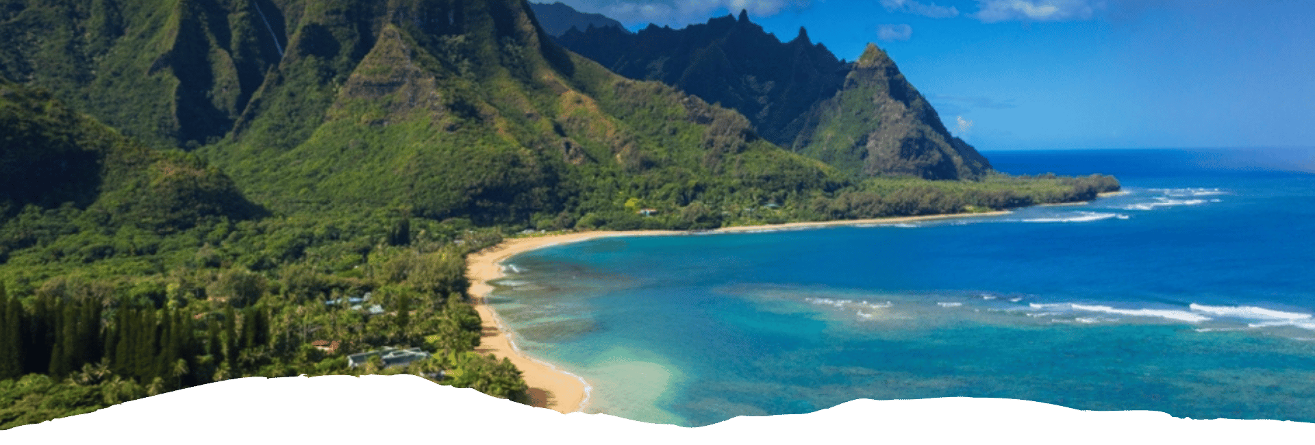 Türkisblaues Meer, goldener Sandstrand und üppig grüne Berge prägen die hawaiianische Küstenlandschaft auf Kauai.