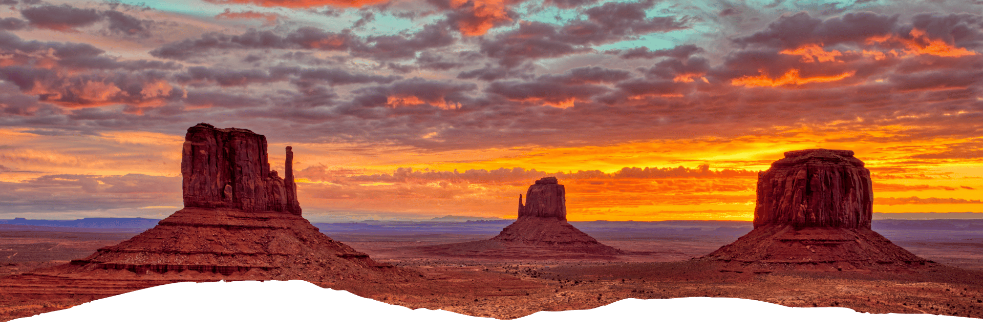 Spektakuläre Felsformationen im Monument Valley leuchten bei Sonnenuntergang vor einer weiten Wüstenlandschaft in Arizona.