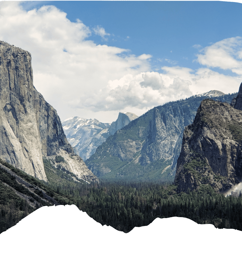 Weites Yosemite-Tal mit markanten Granitwänden, bewaldeten Hängen und schneebedeckten Bergen unter blauem Himmel