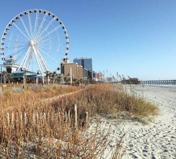 Breiter Sandstrand mit Dünen, Riesenrad und Seebrücke in Myrtle Beach bei einer Rundreise durch Georgia und die Carolinas