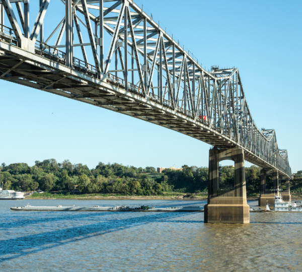 Stählerne Brücke über dem Mississippi bei Natchez mit bewaldetem Ufer und Ausflugsschiffen im klaren Tageslicht