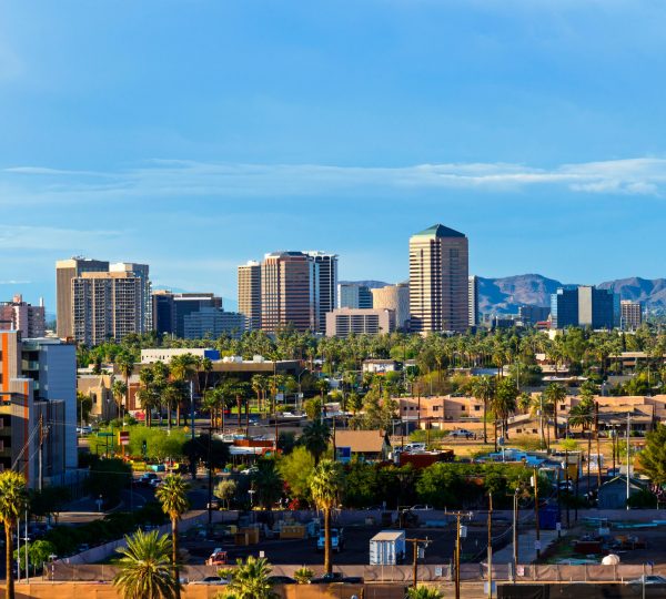 Palmen und moderne Hochhäuser prägen das Stadtbild von Scottsdale, Arizona, vor einer Bergkulisse im Südwesten der USA.