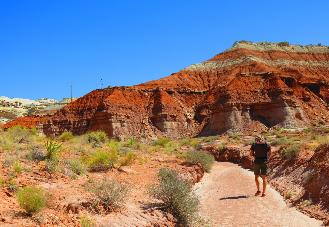 Ein Wanderer folgt einem roten Sandsteinpfad durch die schroffe Landschaft des Capitol Reef National Park in Utah.