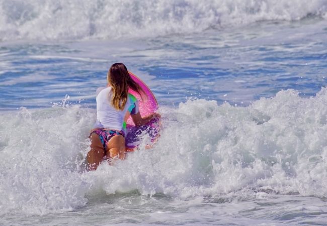 Eine Surferin mit buntem Surfbrett reitet durch hohe Wellen an der Küste von San Diego und genießt das Meer.