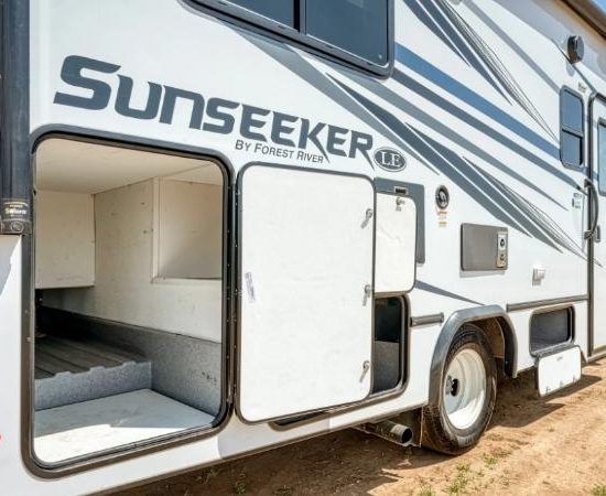 Weißes Sunseeker-Wohnmobil der Mighty Class C mit geöffneter Außenstauraumklappe und geräumigem Ladefach