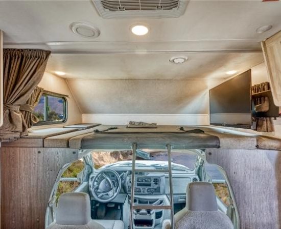 Blick vom Wohnbereich auf Fahrerhaus, Alkovenbett und Queenbett im Road Bear Class C mit drei Schlafplätzen