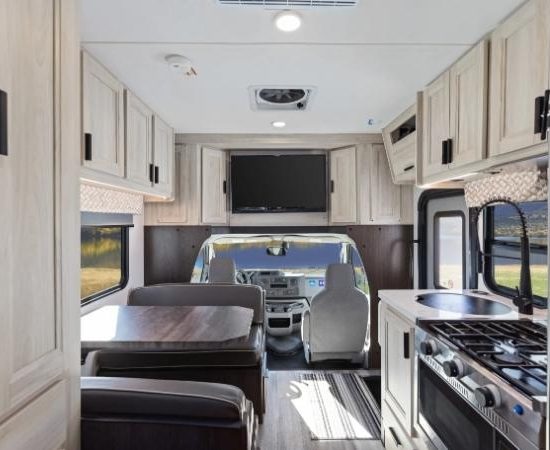 Der Road Bear RV Super Van Camper zeigt helle Holzschränke, Küche, Sitzgruppe und Fahrerbereich.