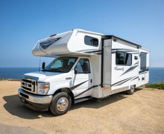 An der Küste steht ein weißes Road Bear RV Wohnmobil mit ausklappbarer Seitenwand und Blick aufs Meer.