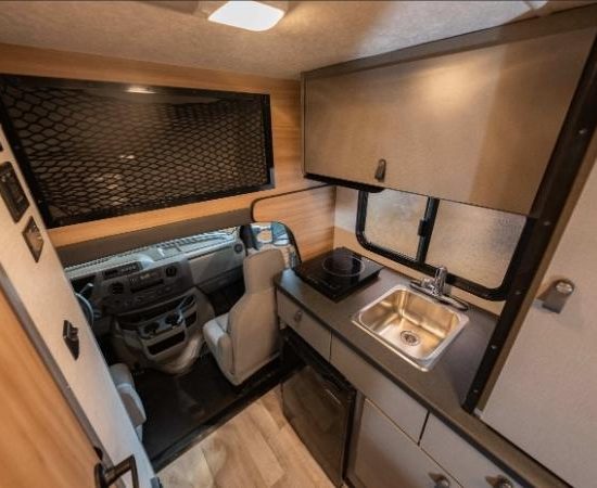 Im Cruise America C18 verbinden sich Fahrerkabine, Küchenzeile mit Spüle und Kochfeld sowie Stauraum im kompakten Aufbau.