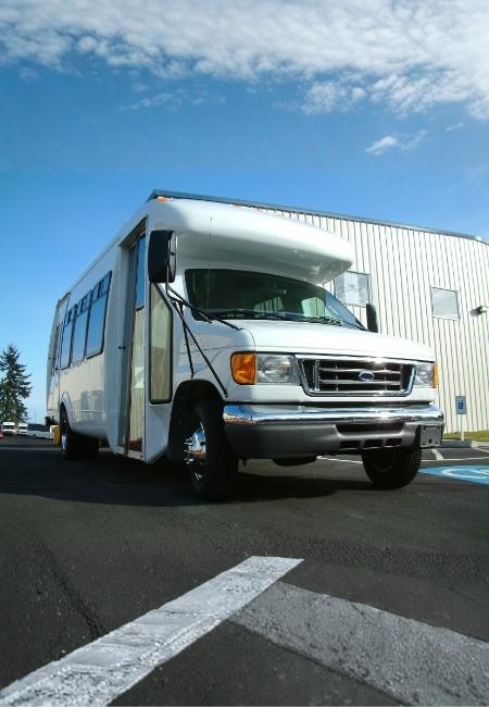 Ein weißes Road Bear RV Wohnmobil steht vor einem Industriegebäude auf Asphalt unter blauem Himmel.