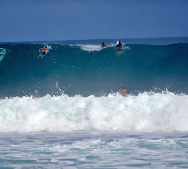 Mehrere Surfer beobachten eine hohe, brechende Welle an der Banzai Pipeline vor Oahu auf Hawaii.
