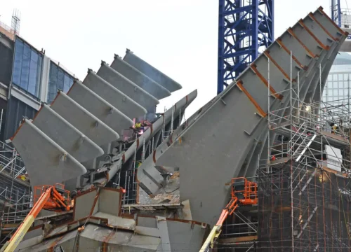 Graue Stahlsegmente und Baugerüste prägen die Montagearbeiten am One World Trade Center in New York.