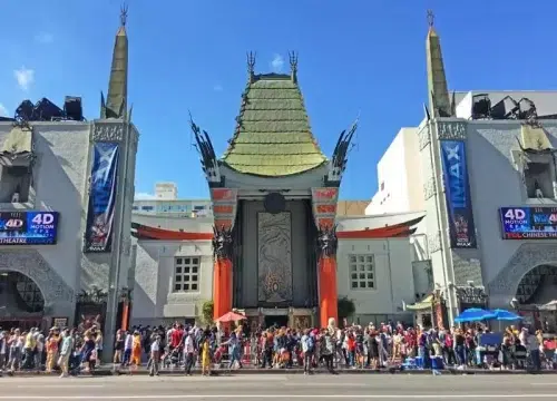Besucher stehen vor dem Chinese Theatre am Hollywood Boulevard in Los Angeles, dessen markante Türme und grünes Dach sichtbar sind.