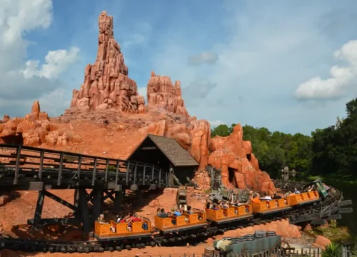 Eine orangefarbene Minenbahn fährt durch die felsige Landschaft von Big Thunder Mountain im Magic Kingdom Orlando.