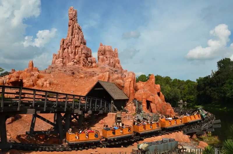 Eine orangefarbene Minenbahn fährt durch die felsige Landschaft von Big Thunder Mountain im Magic Kingdom Orlando.