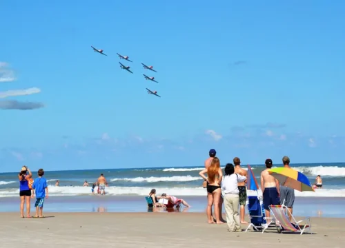 Besucher verfolgen am Strand von Daytona Beach eine Formation mehrerer SNJ-2-Flugzeuge über dem Atlantik bei der Wings and Waves Airshow.