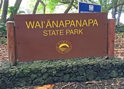 Ein Eingangsschild weist auf den Waiʻānapanapa State Park an der Road to Hana auf Maui, Hawaii, hin.