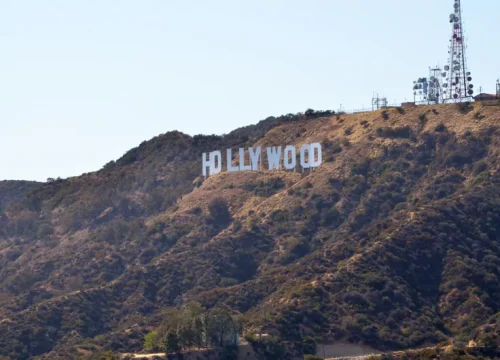 Weiße HOLLYWOOD-Buchstaben stehen am trockenen Hügel im Griffith Park über Los Angeles, umgeben von Funkmasten.