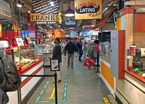 Belebter Marktgang im Reading Terminal Market mit Frank’s The Original und Latino Kitchen in Philadelphia