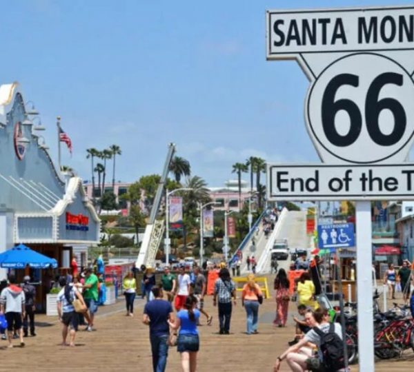 An der lebhaften Strandpromenade von Santa Monica markiert ein Schild den Endpunkt der Route 66 am Pazifik.
