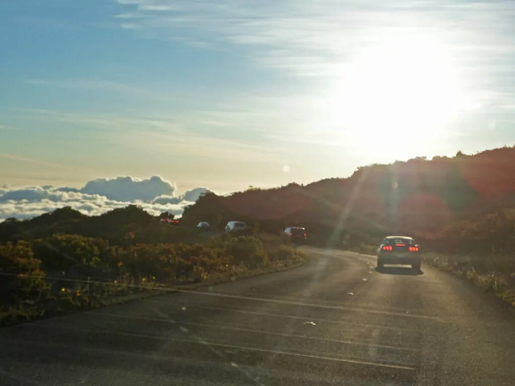 Autos fahren im frühen Morgenlicht auf der kurvenreichen Straße zum Sonnenaufgang am Haleakalā auf Maui.