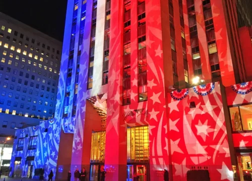 Nächtliche Weihnachtsbeleuchtung taucht das Rockefeller Center in New York in rote und blaue Farben mit Sternmotiven.