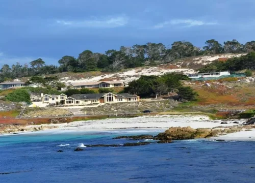 Felsige Küste mit weißen Sandflächen, türkisblauem Wasser und Häusern am 17-Mile Drive bei Pebble Beach