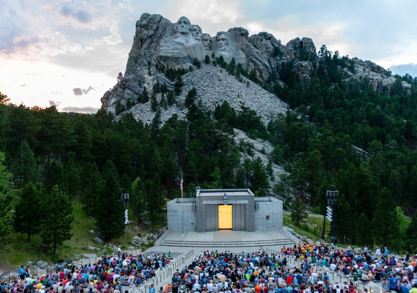 Mount Rushmore am Abend mit einem Publikum davor.